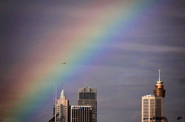Боинг 737 пролетает через радугу над центральным деловым районом Сиднея