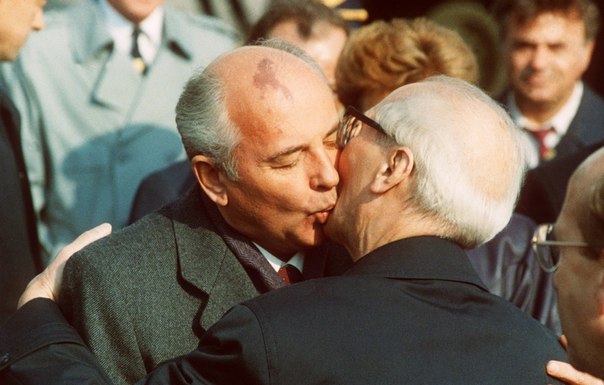 Культовый поцелуй Горбачева и президента Восточной Германии Эриха Хонеккера 7 октября 1989 года. Через 11 дней Хонеккера сместили с поста президента, а Берлинская стена пала, ознаменовывая кончину ГДР.