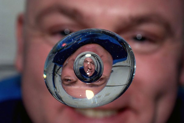 Снимок капли в невесомости, сделанный на Международной космической станции. На заднем плане нидерландский астронавт Андре Кёйперс.