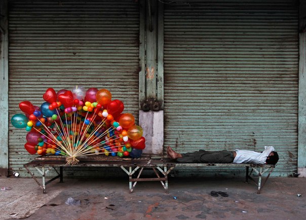 Торговец воздушными шариками спит возле магазина в старом квартале в Дели.