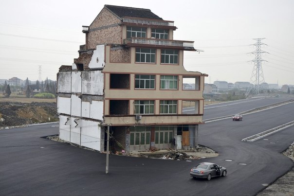 Новая дорога в провинции Чжэцзян, Китай. Пожилая пара, проживающая в этом доме, отказалась подписывать соглашение на снос дома из-за слишком низкой, по их мнению, компенсации. 