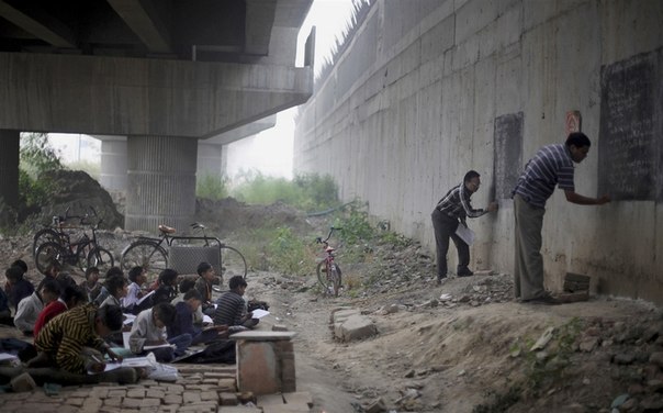 Фотограф Альтаф Кадри обнаружил в Нью-Дели, Индия, необычную школу. В ней есть учителя, ученики, две доски, стул и больше ничего — ни парт, ни самого здания школы. Дети из трущоб познают азы математики, учатся писать и читать прямо на улице под мостом.