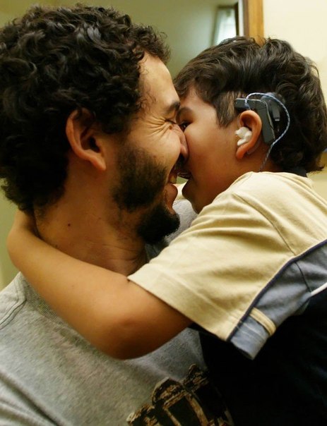 Счастливый отец держит на руках сына, который обрел слух и услышал своего отца впервые в жизни.