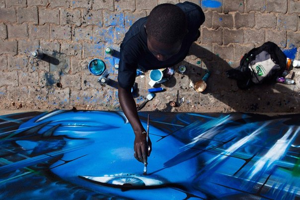 Художник рисует граффити возле шоссе в Дакаре, Сенегал