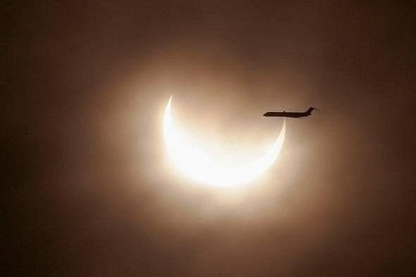 Самолет пролетает мимо солнечного диска во время затмения.