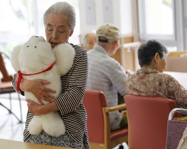 Сацуко Яцузако обнимает своего робота-тюленя. Такие игрушки, издающие звуки и реагирующие на движение, стали единственным утешением для многих японцев из домов престарелых, переживших землетрясение в Фукусиме и цунами