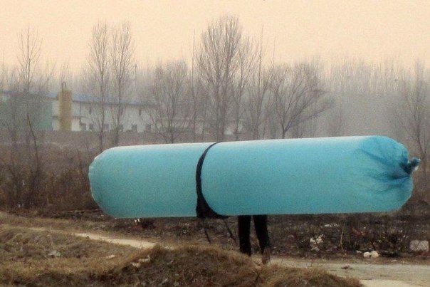 Женщина несет шестиметровый полиэтиленовый пакет с природным газом, провинция Шаньдун, Китай.